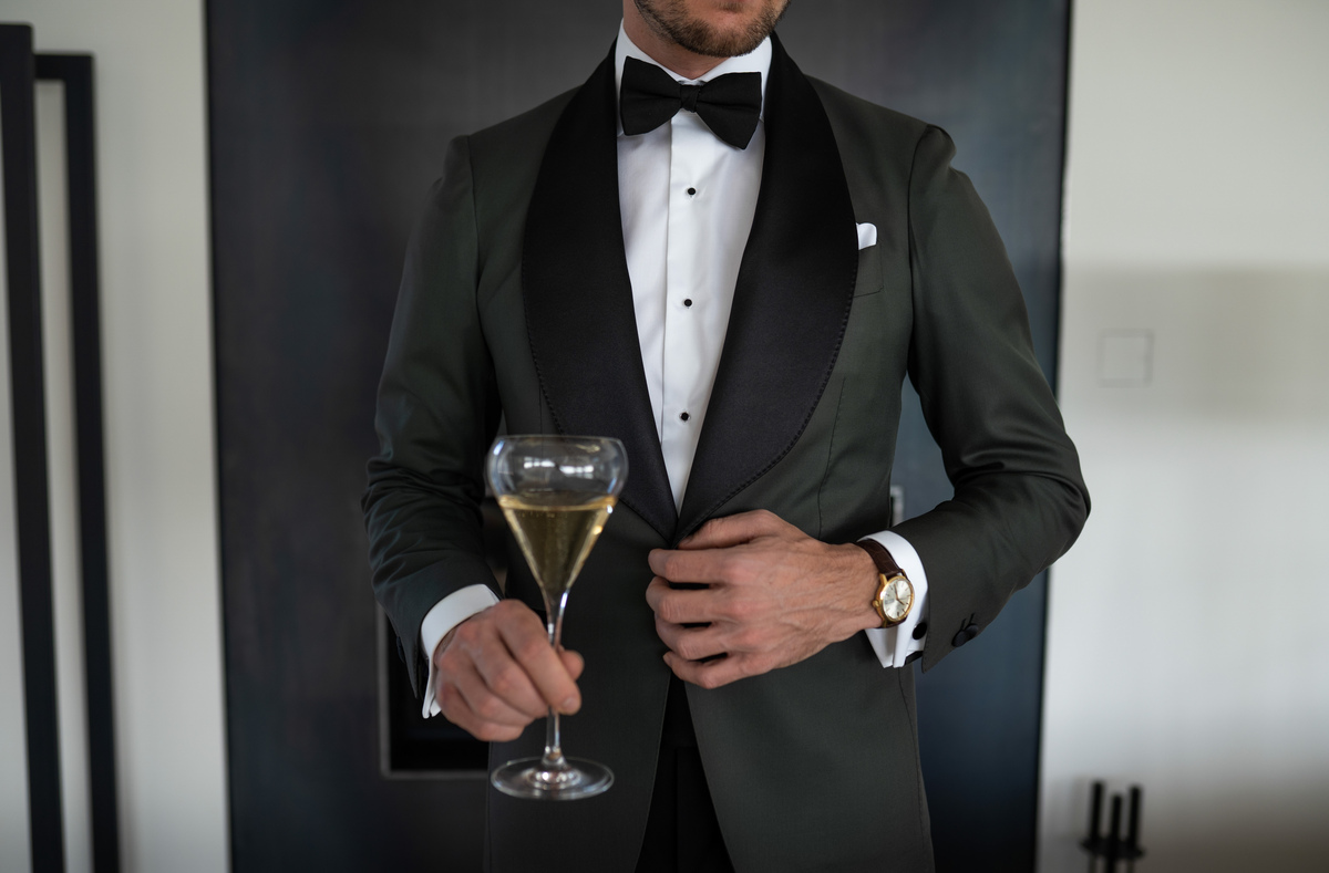 Classy man with a cocktail glass is wearing a green Amarcord suit